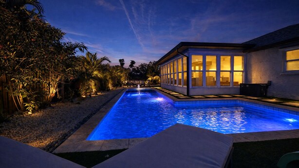 A swimming pool with a view of a house and surrounding vegetation. - Welcome to The Florida Rooms- Your Relaxing Retreat Near the Gulf! New Pool Spa! (Bradenton)