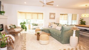 A modern living room with a sectional sofa, wicker chairs, a coffee table, and a floor lamp. - Welcome to The Florida Rooms- Your Relaxing Retreat Near the Gulf! New Pool Spa! (Bradenton)
