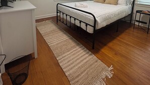 A bedroom with a bed, a desk, a ceiling fan, and a window with blinds.