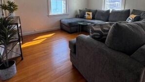 A living room with a sectional sofa, a small side table, and a potted plant.