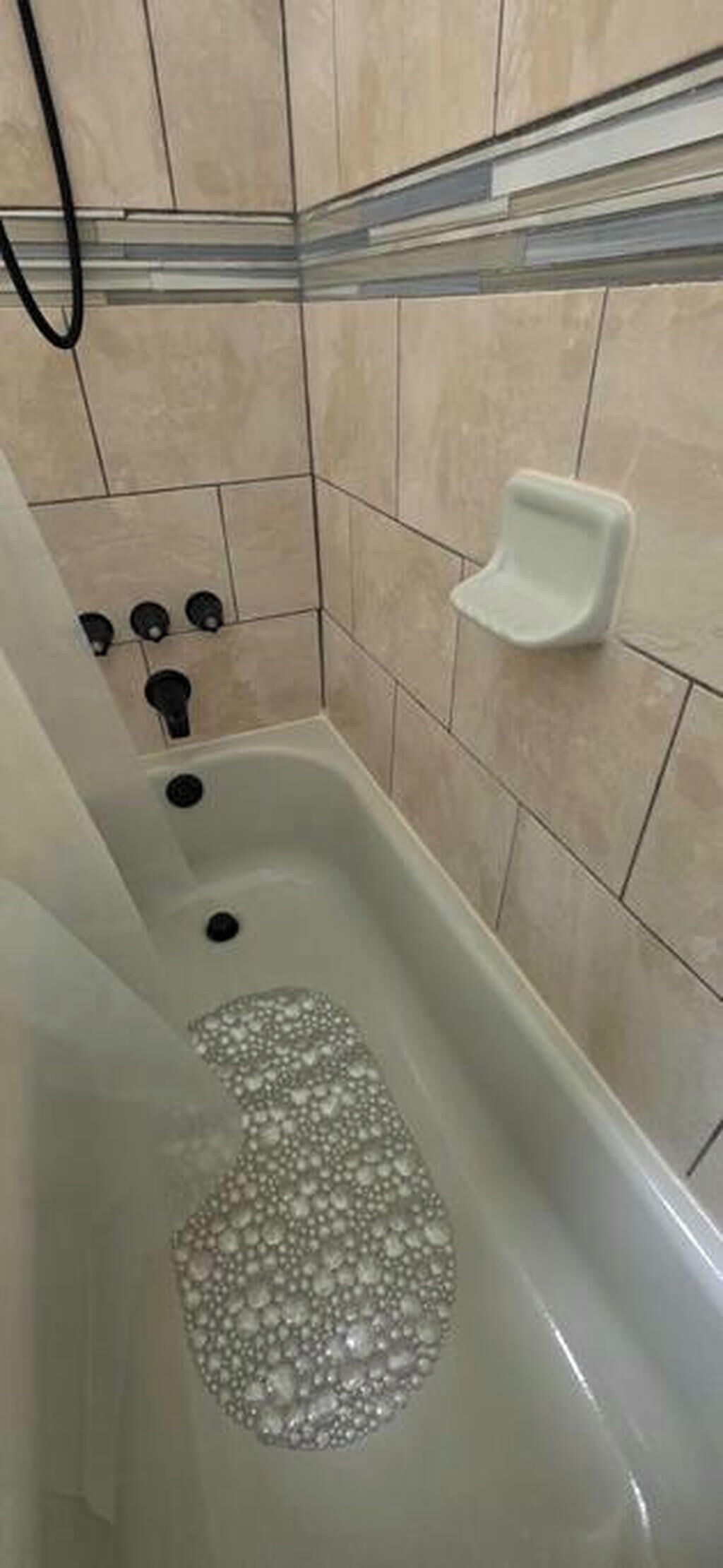 A bathtub with bubbles, a soap dish, and a showerhead.