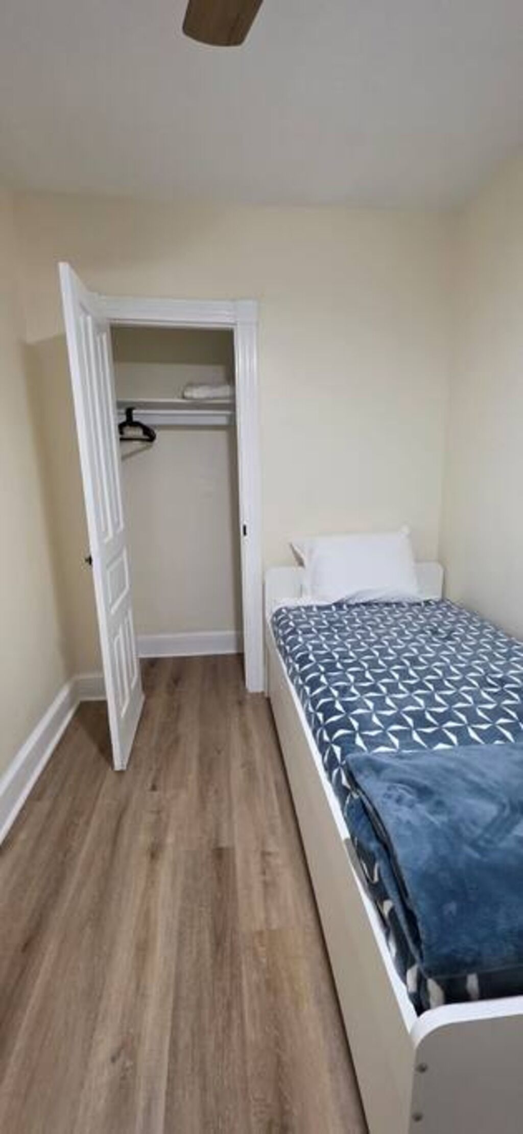 Une chambre à coucher comprenant un lit, une armoire et une porte donnant sur une autre pièce.