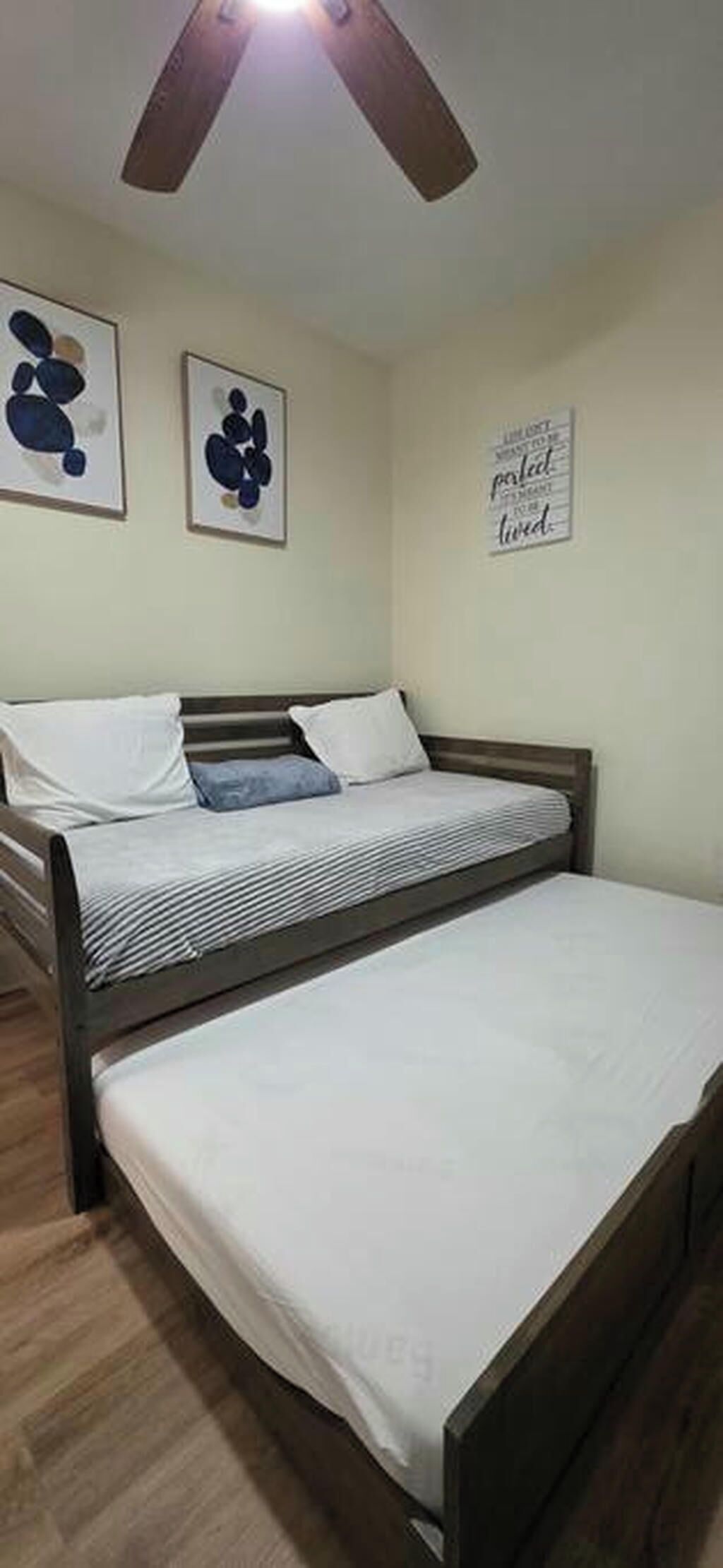 Ein Schlafzimmer mit einem Bett, einem Deckenventilator und zwei Wandbildern.