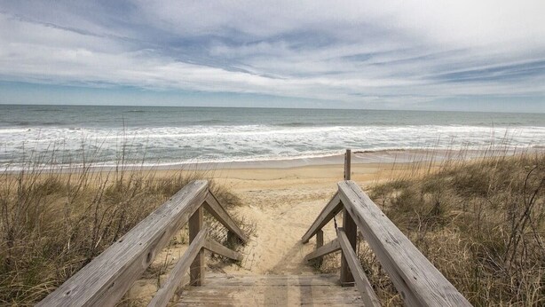 A wooden boardwalk leading to a beach with ocean views.