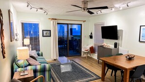 A modern living room with a sofa, a dining table, a TV, and a ceiling fan.