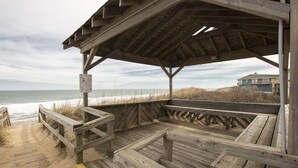 A wooden beach boardwalk leading to a covered area with benches.