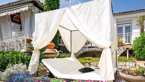A sunlit outdoor seating area with a cushioned lounge chair, a white canopy, and a variety of colorful flowers. - Villa Nika by Interhome (Opatija/Ika)