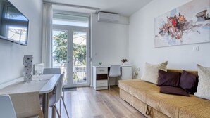 A modern living room with a sofa, a dining area with a table and chairs, a TV mounted on the wall, and a sliding glass door leading to an outdoor area. - Villa Nika by Interhome (Opatija/Ika)