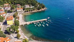 An aerial view of a coastal town with a marina, clear turquoise waters, and buildings with red-tiled roofs. - Villa Nika by Interhome (Opatija/Ika)