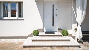 A modern building with a white exterior, a door with a vertical handle, and a small window with a view of a tiled roof. - Villa Nika by Interhome (Opatija/Ika)