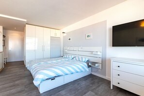 Une chambre moderne avec un lit, des tables de chevet, une armoire et un téléviseur.
