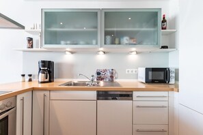 Een moderne keuken met een vaatwasser, een koffiezetapparaat, een magnetron en een kast met glazen deuren.