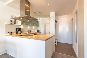 A modern kitchen with a central island, stainless steel range hood, and built-in appliances.