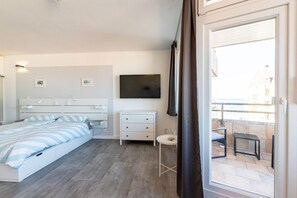 Une chambre à coucher comprenant un lit, des tables de chevet, une télévision et un balcon avec une table et des chaises.