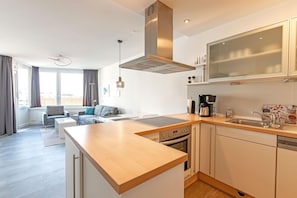 A modern kitchen with a built-in oven, a coffee maker, and a large window.