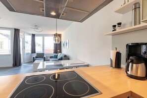 Une cuisine moderne équipée d’une cuisinière intégrée, d’une machine à café et d’une bouilloire posées sur le plan de travail.
