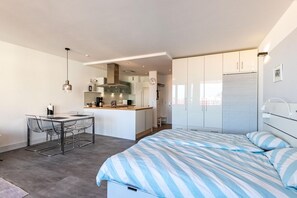 Une chambre moderne dotée d’un grand lit, d’un coin repas séparé et d’une kitchenette.