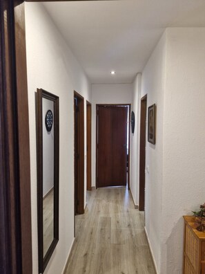 A hallway with wooden doors, a dartboard, and a small wooden cabinet. - Nice Portim o Flat Near Marina and Beach (Portimão)
