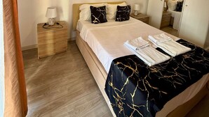 A neatly arranged hotel room with a bed, bedside tables, a wardrobe, and a ceiling light.