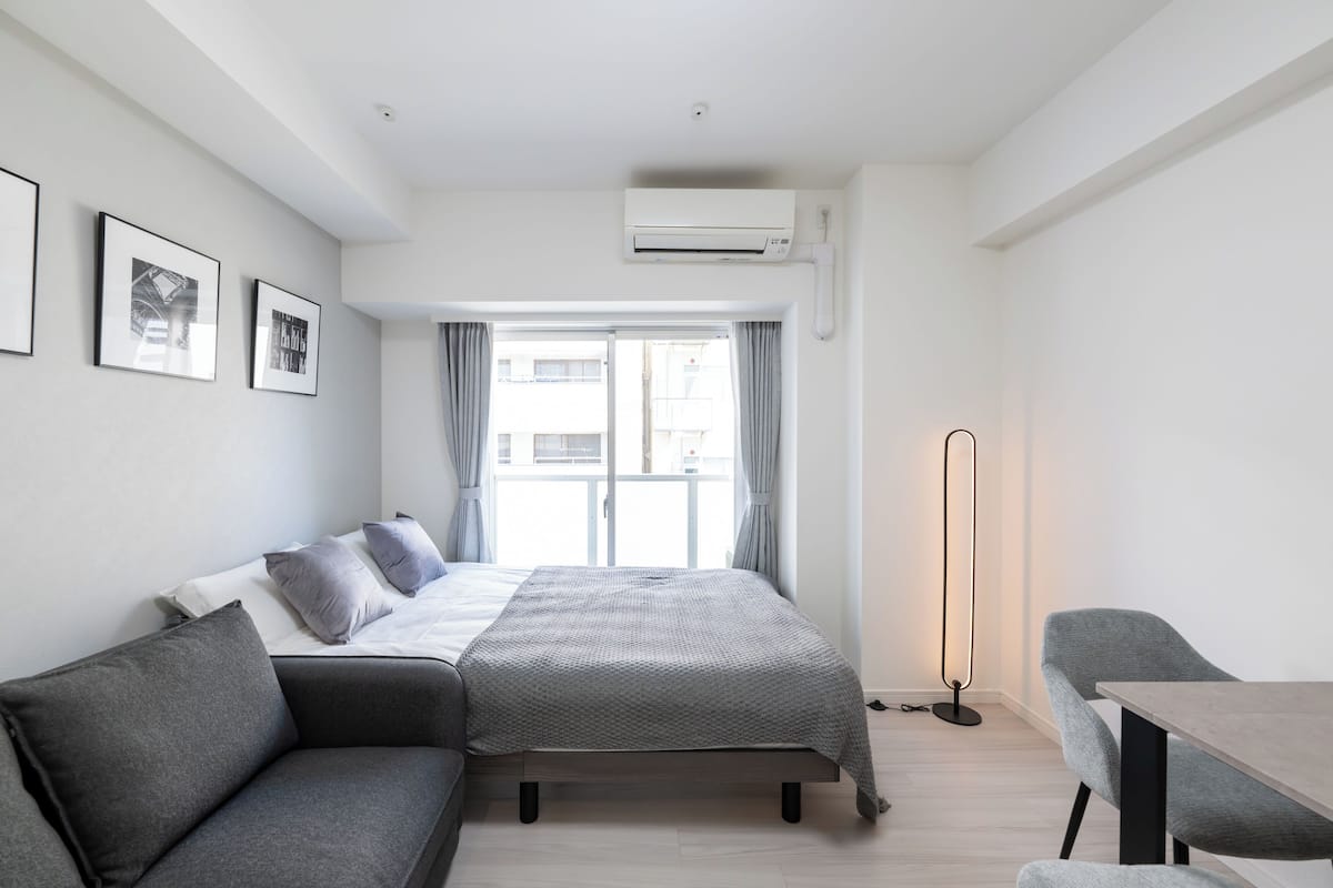 A modern bedroom with a bed, a sofa, a table, and a floor lamp.