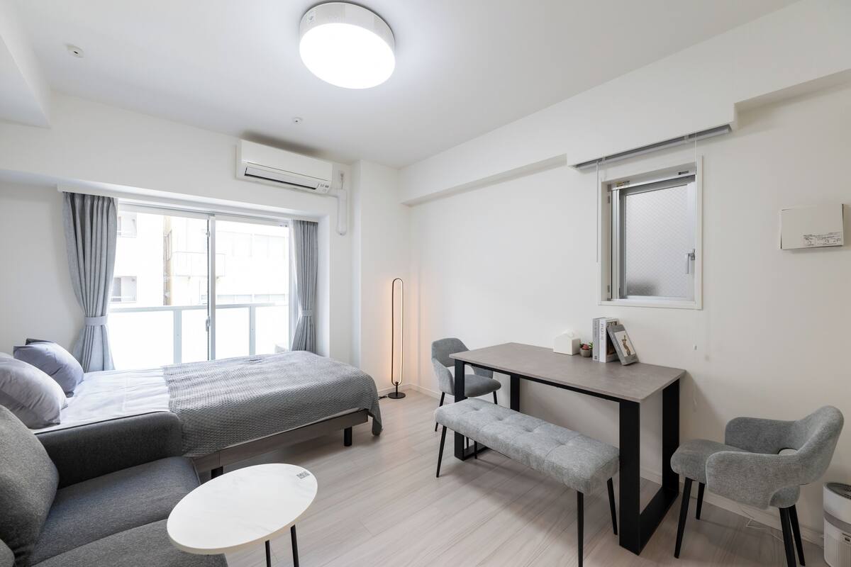 A modern hotel room with a bed, a desk, a chair, a bench, and a small table.