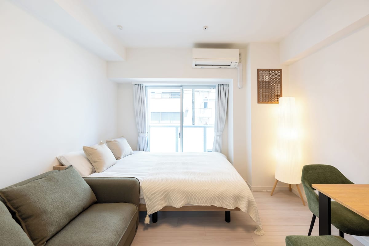 A hotel room with a bed, a sofa, a table, and a lamp.