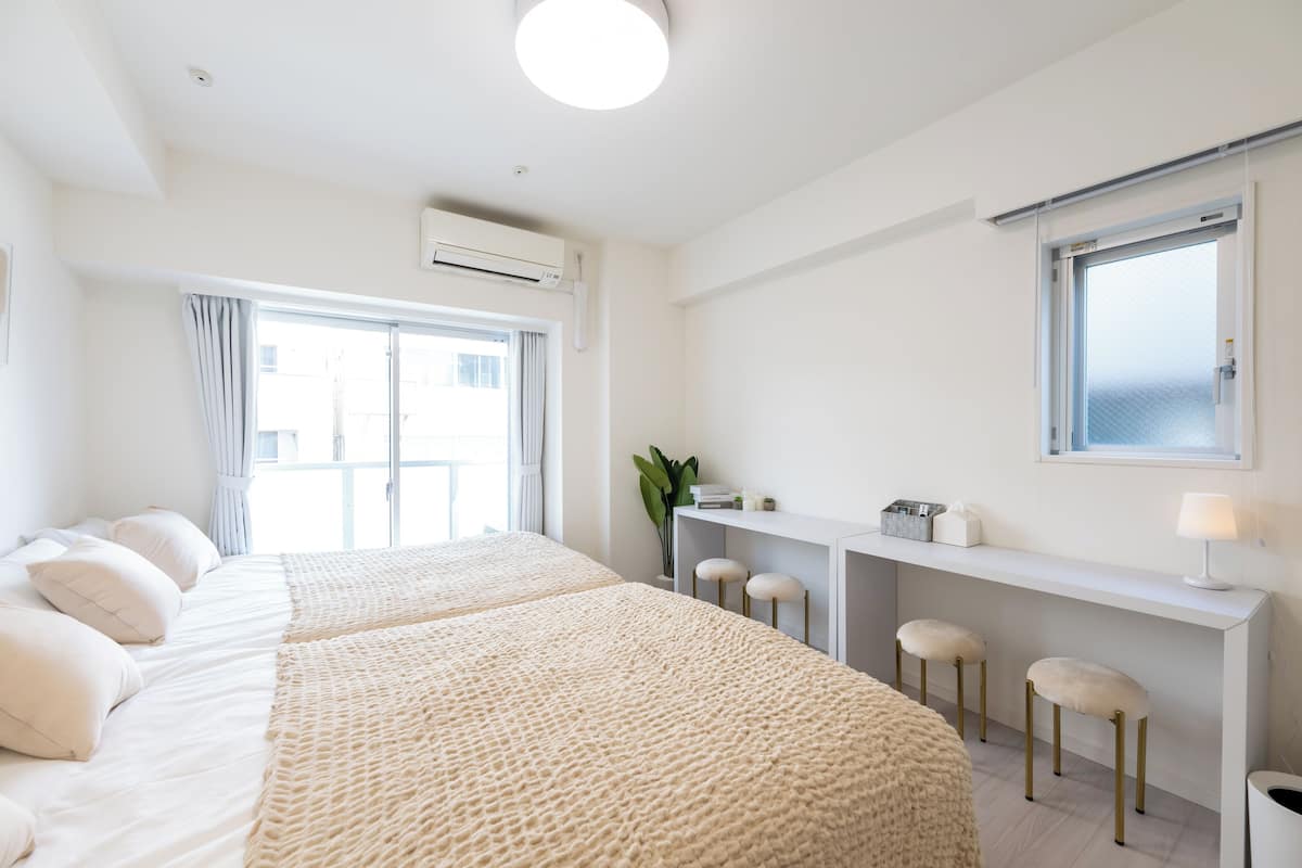 A modern hotel room with two beds, a desk, and a window.
