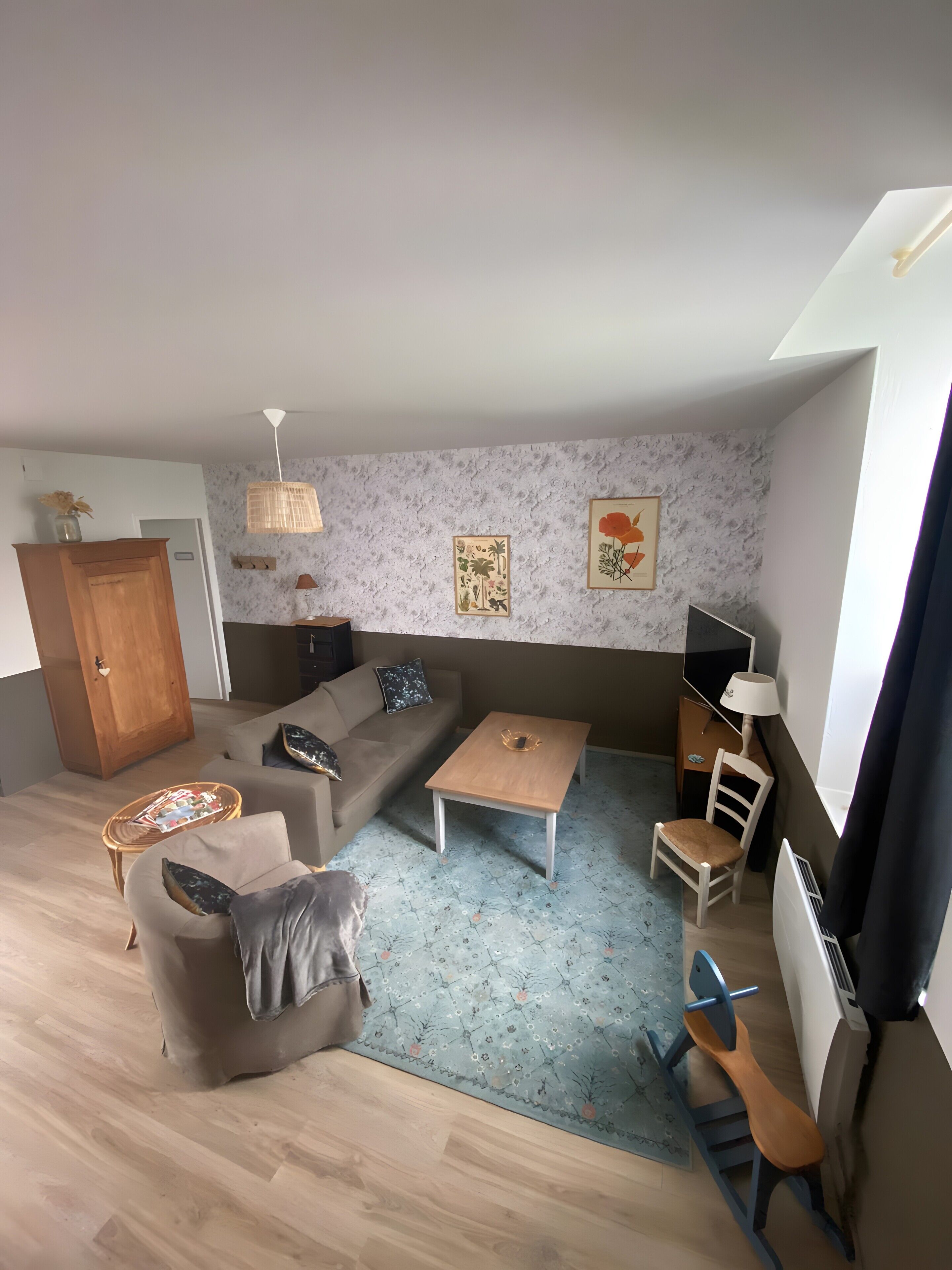 Een woonkamer met een bank, een salontafel, een televisie en een eethoek met een stoel en tafel.