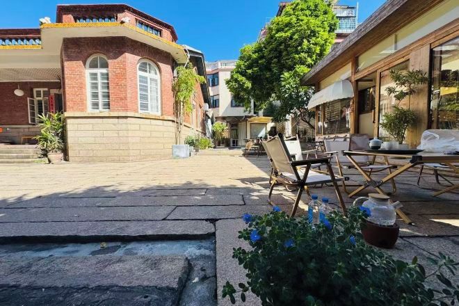 Un patio con sendero de piedra, asientos al aire libre y un árbol.