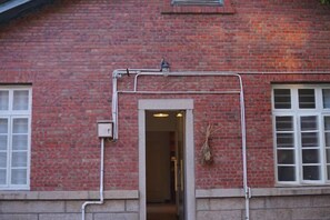 A red brick building with a doorway, a window, and a small vent above the door. - No.54·Nanyang Old Villa (Quanzhou)
