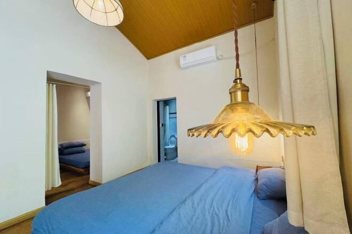 Une chambre à coucher avec un lit, une lampe suspendue, une porte et un appareil de climatisation.