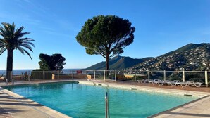 Una piscina con vista despejada al mar y una montaña al fondo.