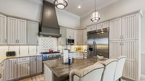 A modern kitchen with white cabinetry, stainless steel appliances, and a marble island. - Welcome to The Dream Getaway (Kissimmee)