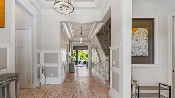 A long, narrow hallway with wooden flooring, white walls, and a staircase on the right. - Welcome to The Dream Getaway (Kissimmee)