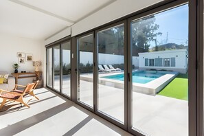 A modern interior with large sliding glass doors leading to a swimming pool area. - Villa 'Casa Rural Acogedora Y Con Estilo' with Mountain View, Wi-Fi and Air Conditioning (Málaga)