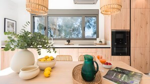 A modern kitchen with wooden cabinets, a large window, and a dining area with a table set for two.