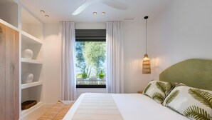 A bedroom with a large bed, a bedside table, a hanging light fixture, and a window with curtains.