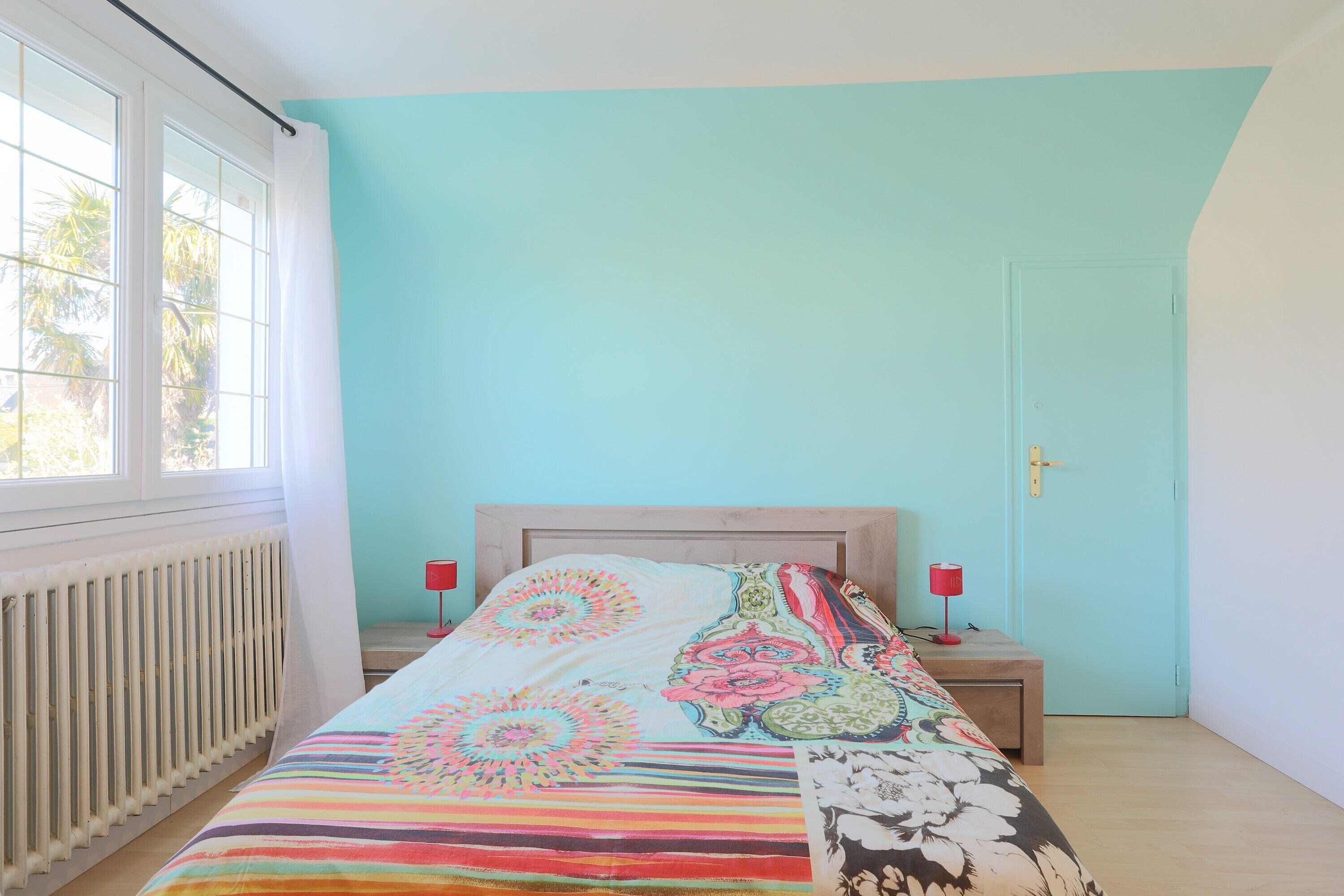 Une chambre à coucher avec un lit, deux tables de chevet, une fenêtre et une porte.