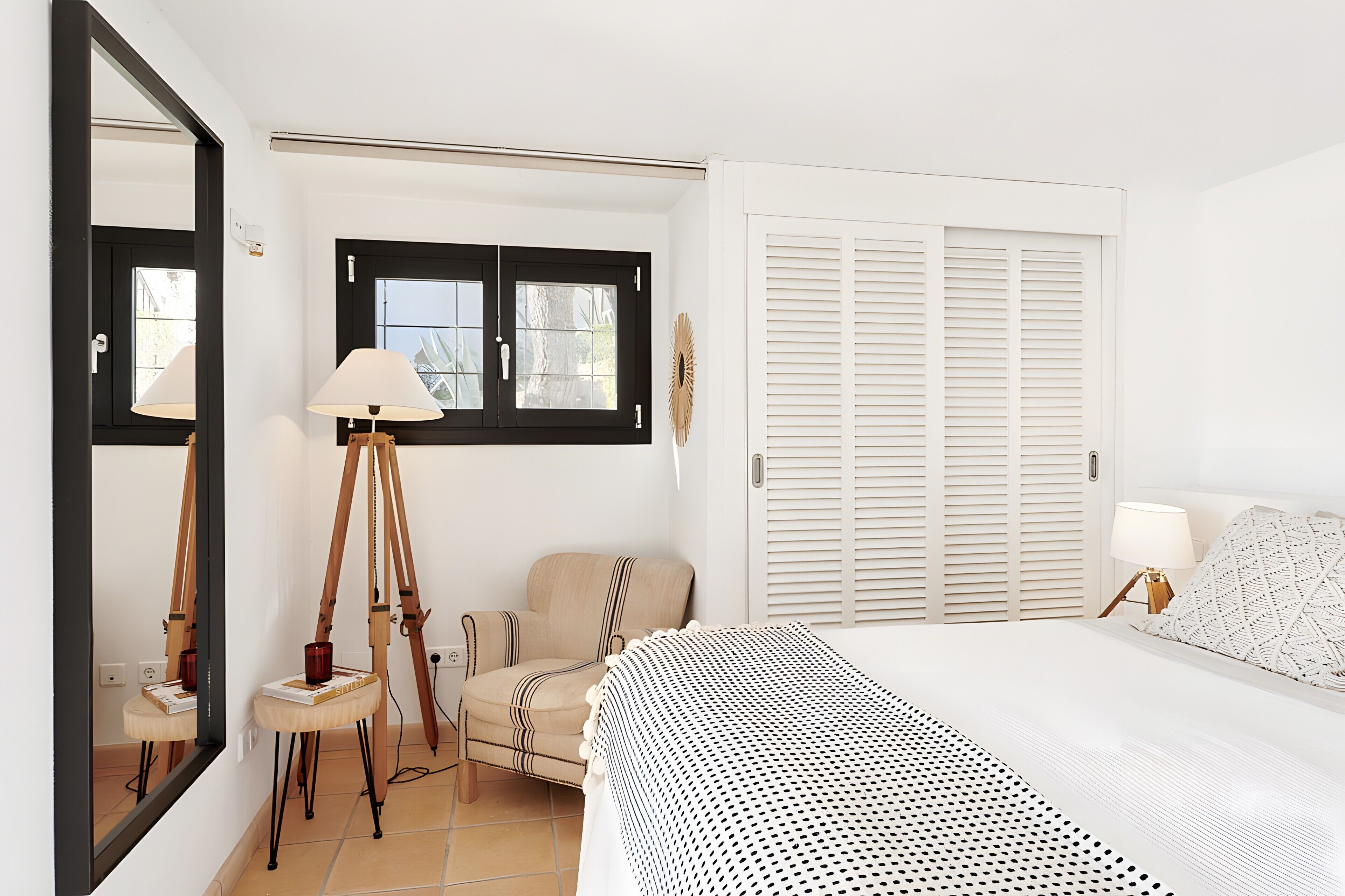Une chambre à coucher avec un lit, une chaise, une lampe, une fenêtre et une armoire.