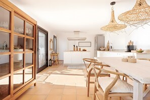 A modern kitchen with a dining area, wooden cabinets, and a large window.