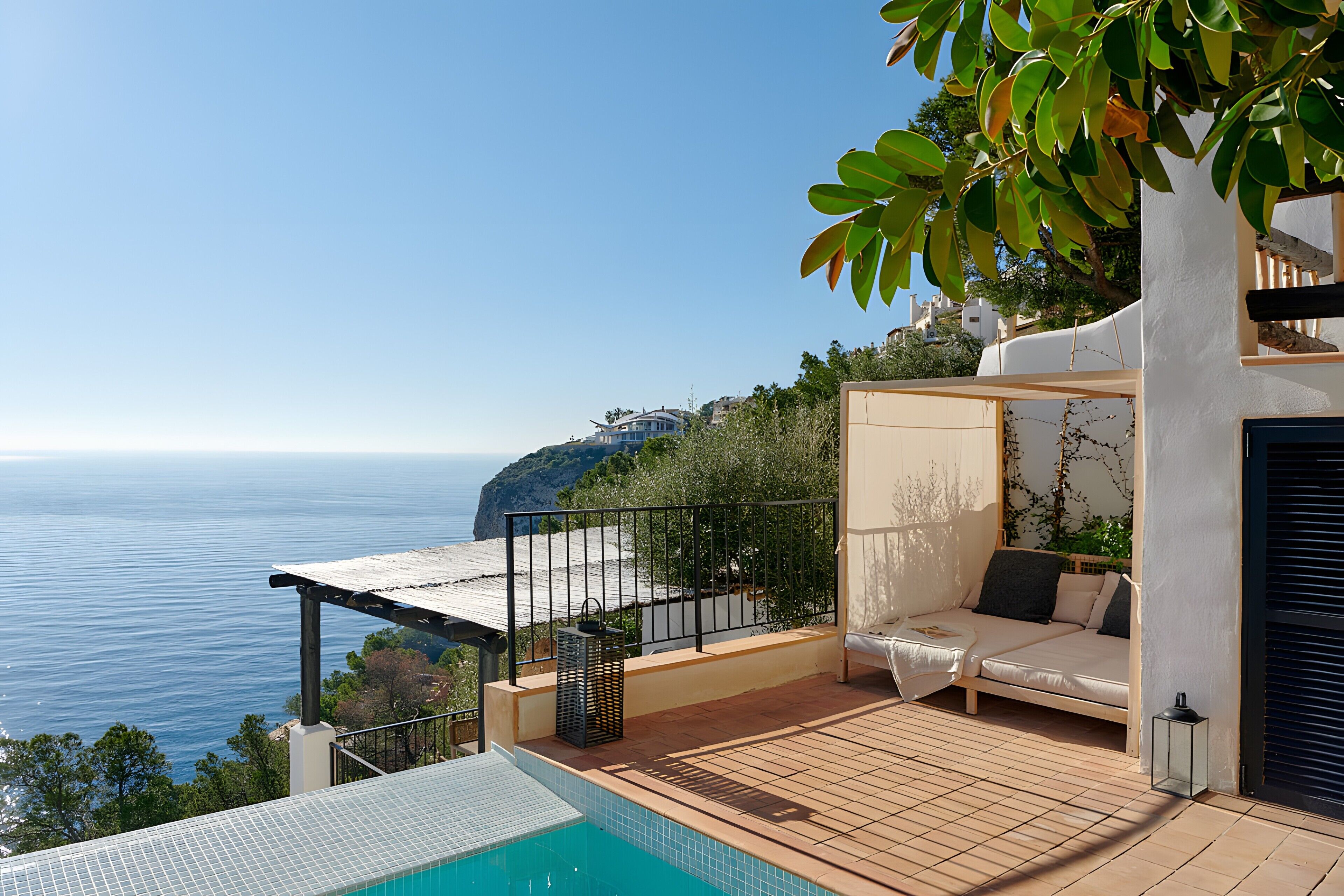 Una terraza con piscina, sofá y vista al mar.
