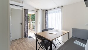 Et moderne værelse med et træbord, sorte stole, en grå sofa og en skydedør af glas til et udendørs område.