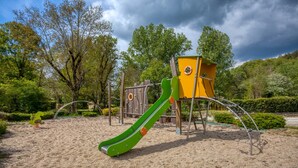 A playground with a green slide and yellow climbing structures. - Mobile Home "Calvi": Holidays in Dordogne, Shared Pool & Mini-Farm near Sarlat (Bouzic)