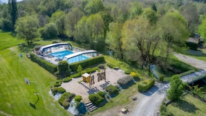 Eine Vogelperspektive auf ein Anwesen mit Swimmingpool, Tennisplatz und gepflegtem Garten.