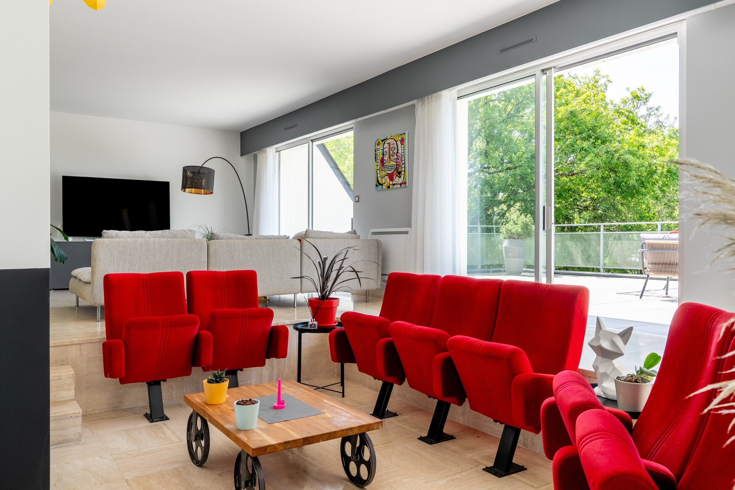Un salon moderne avec des fauteuils rouges, une table basse en bois et un téléviseur.