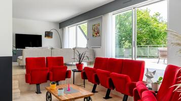 Un salon moderne avec des fauteuils rouges, une table basse en bois et un téléviseur.
