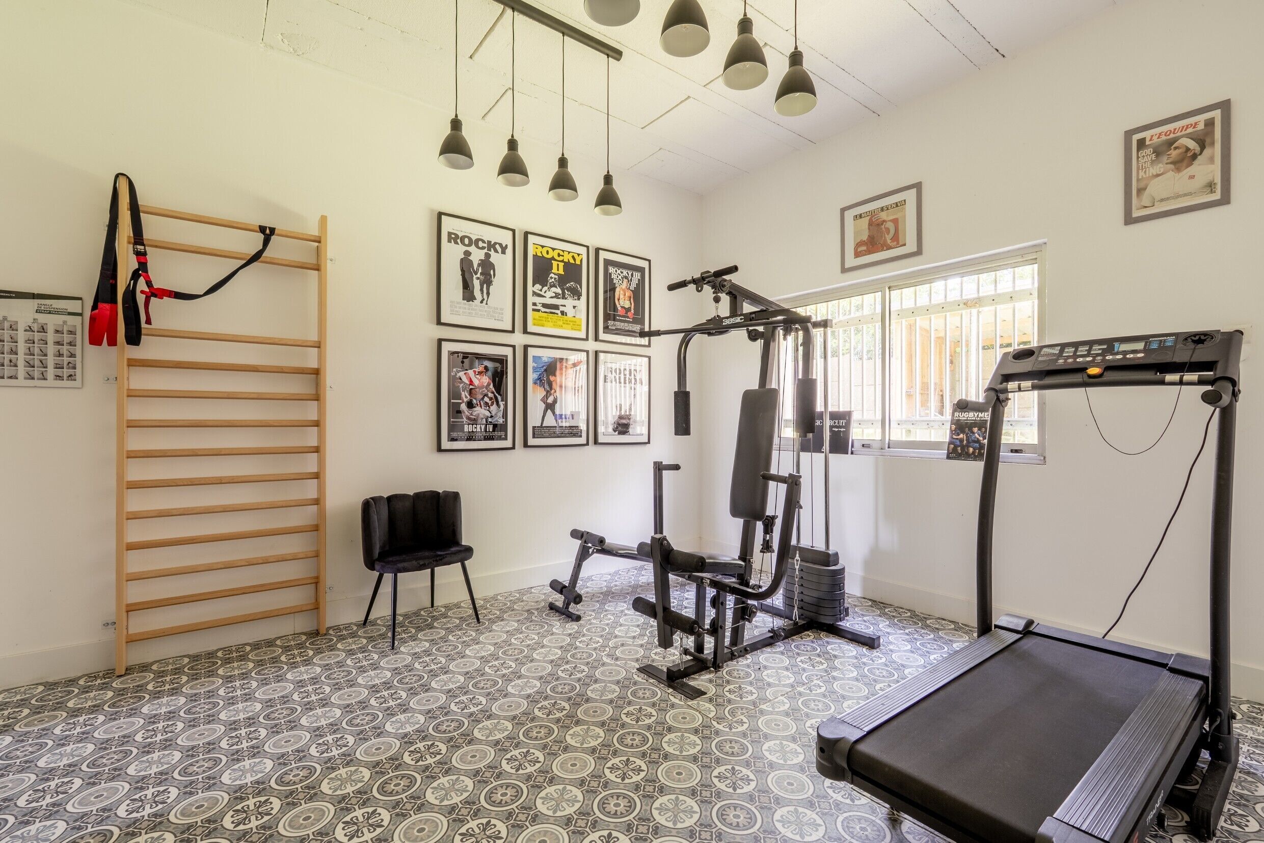 Ett gym med löpband, styrketräningsmaskiner, en stång för chins och ett golv med ett mönster.