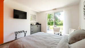 A bedroom with a bed, a desk, a chair, a TV, and a sliding glass door leading to a balcony. - Kerwall – Double Room with Shared Pool, Private Terrace and Wi-Fi (Malville)