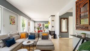 A modern living room with a grey sectional sofa, two round tables, and a large mirror. - Kerwall – Double Room with Shared Pool, Private Terrace and Wi-Fi (Malville)