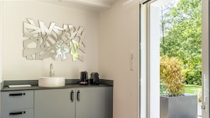 A modern bathroom with a grey cabinet, a white sink, and a decorative metal wall piece. - Kerwall – Double Room with Shared Pool, Private Terrace and Wi-Fi (Malville)